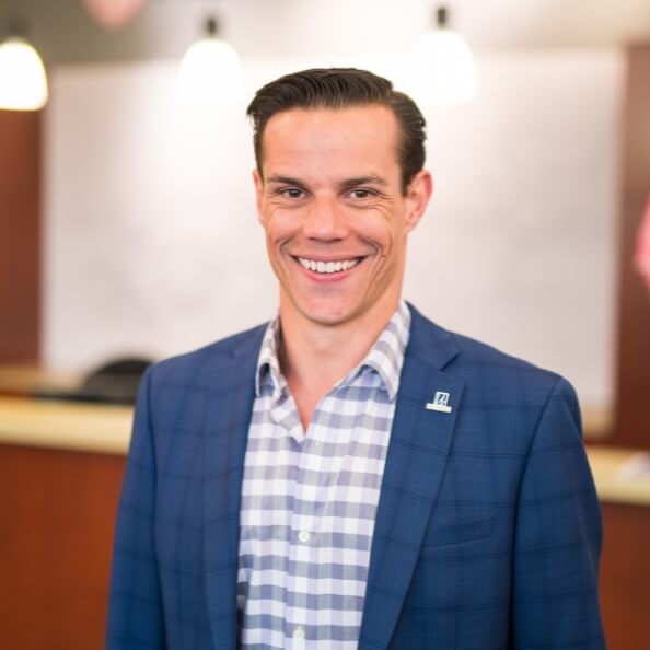 Andrew Colabella smiles in business casual in an academic building.